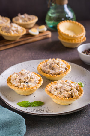 Appetizing tartlets with egg, canned tuna and onion salad on a plate on the table vertical viewの写真素材