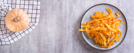 Homemade organic baked pumpkin chips on a plate on the table top view web bannerの写真素材