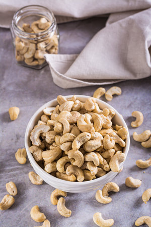Dried cashew nuts in a bowl on the table for a vegetarian diet vertical viewの写真素材