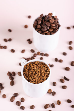Choice between instant coffee and roasted coffee beans in cups on pink background vertical viewの写真素材