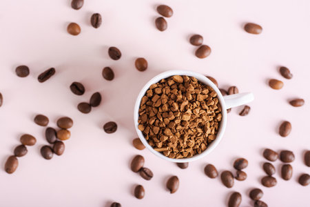 Dry granules of instant coffee in a cup on a pink background top viewの写真素材