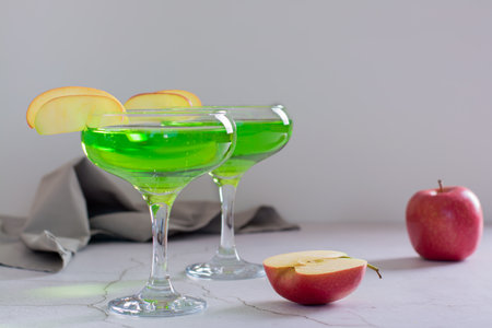Homemade green apple martini cocktail with apple pieces in glassesの写真素材