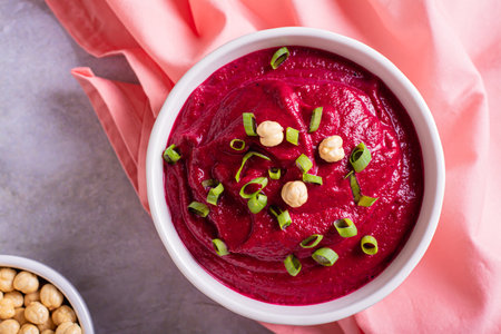 Close up of beetroot hummus in a bowl and chickpeas on the table top viewの写真素材