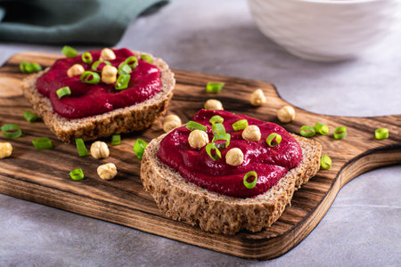 Homemade rye bread sandwiches with beetroot hummus and herbs on a cutting boardの写真素材