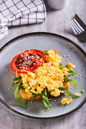 Bruschetta with scrambled egg, arugula, tomato and sesame on a plate vertical viewの写真素材