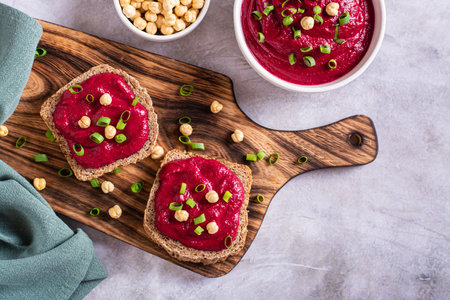 Homemade rye bread sandwiches with beetroot hummus and herbs on a cutting board top viewの写真素材