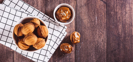 A bowl of cookies nuts filled with boiled condensed milk on a board top view web banner