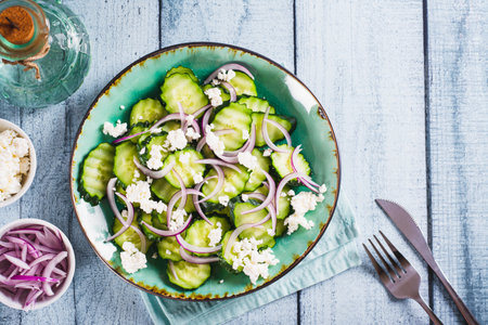 Fresh cucumber, ricotta and red onion salad on a plate on the table top viewの写真素材