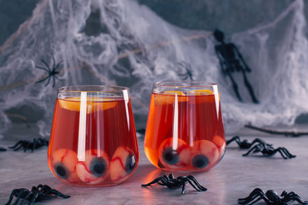 Non alcoholic red cocktail with eyeballs and orange in glasses on the tableの写真素材