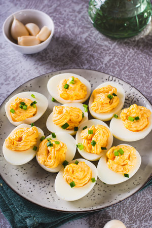 Boiled eggs stuffed with yolk, cheese, garlic and mayonnaise on a plate vertical view