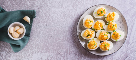 Boiled eggs stuffed with yolk, cheese, garlic and mayonnaise on a plate top view web banner