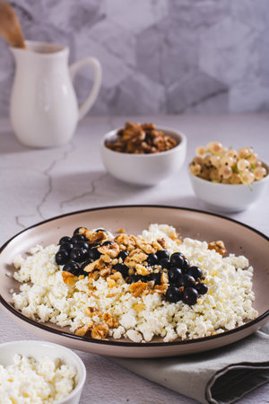 Soft cottage cheese with blackcurrant and walnuts on a breakfast plate vertical viewの写真素材