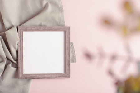 Empty photo frame and blurred branch on gray pink background top viewの写真素材