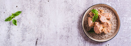 Canned tuna fish meat and basil on a plate on the table top view web banner