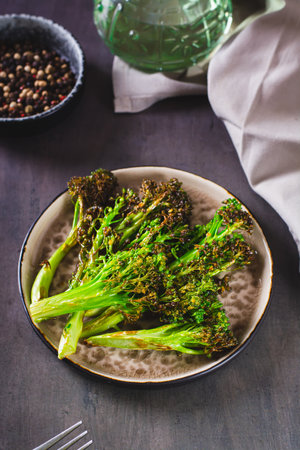 Roasted fresh broccoli sprouts in oil on a plate on the table vertical viewの写真素材