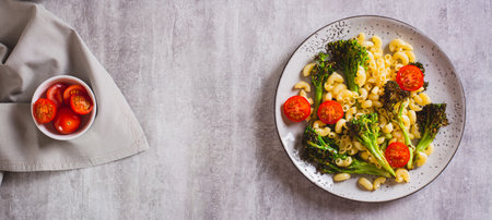 Salad of pasta, tomatoes and fried broccoli sprouts on a plate on the table top view web bannerの写真素材