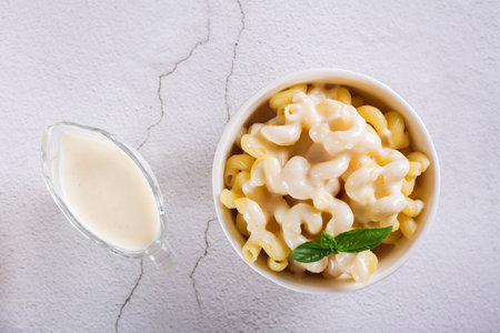 Close up of appetizing pasta with cheese sauce and basil in a bowl on the table top viewの写真素材