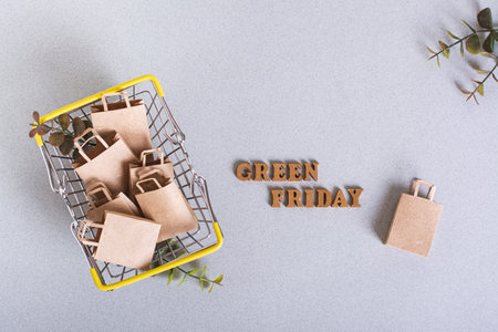Green Friday inscription and paper bags in a shopping cart on a green background top viewの写真素材