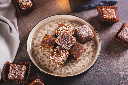 Sugar free candies made from fruit paste, nuts and sesame seeds on a plateの写真素材