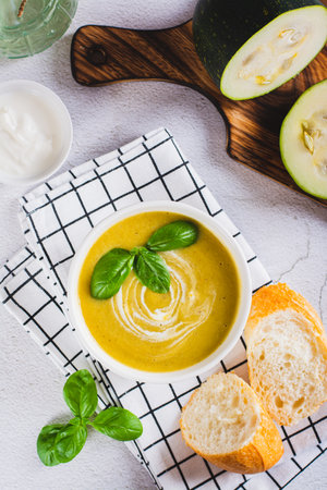 Delicious zucchini soup puree in a bowl and pieces of bread on the table top and vertical viewの写真素材