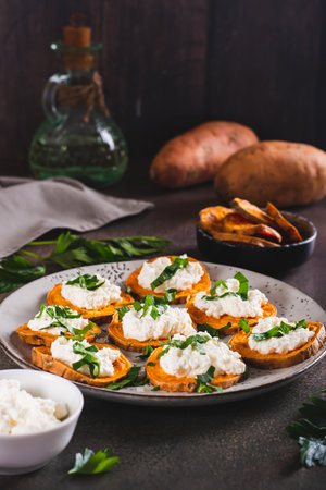 Pieces of baked sweet potato with ricotta and herbs on a plate on the table vertical viewの写真素材
