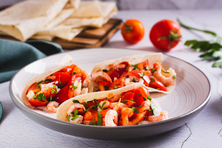 Vegetarian mini tacos with tomatoes, shrimp and herbs on a plate on the tableの写真素材