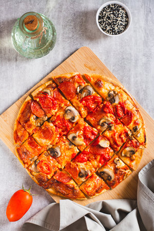 American St. Louis Style pizza with bacon, mushrooms and tomatoes on a board top and vertical viewの写真素材