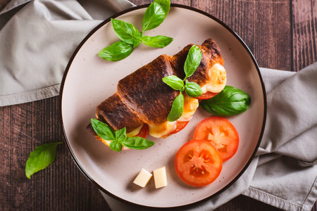 Close up of croissant caprese sandwich baked with tomatoes and cheese on a plate top viewの写真素材