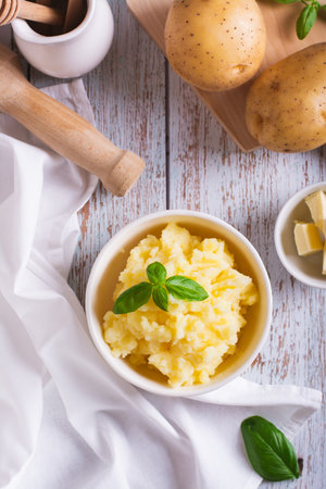 Bowl with delicious homemade mashed potatoes and basil on the table top and vertical viewの写真素材