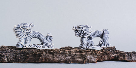 Ceramic dragons on tree bark on gray background for Chinese New Year web bannerの写真素材