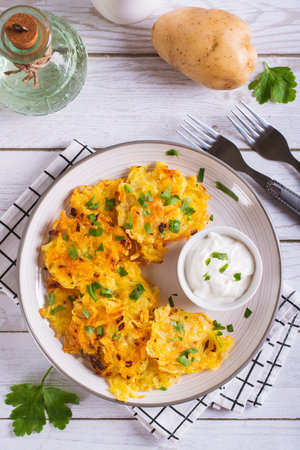Traditional potato latkes with greens and sauce on a plate on the table top and vertical viewの写真素材