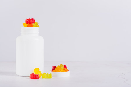 Bottle with gummy vitamin supplements in the shape of bears on the table