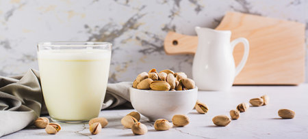 Lactose-free pistachio milk in a glass and nuts on the table web bannerの写真素材