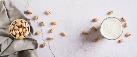 Alternative vegetarian pistachio milk in a glass and nuts on the table top view web bannerの写真素材