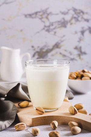 Lactose-free pistachio milk in a glass and nuts on the table vertical viewの写真素材