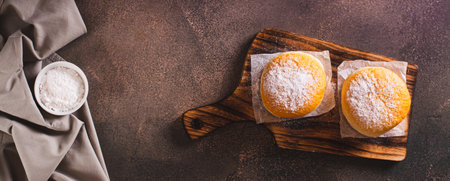 Fresh donuts with powdered sugar and sweet filling on a plate on the table top view web banner