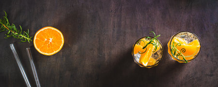 Hard seltzer with ice, orange and rosemary in glasses on the table top view web bannerの写真素材