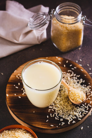 Alternative healthy rice milk in a glass and rice cereal on the table vertical viewの写真素材