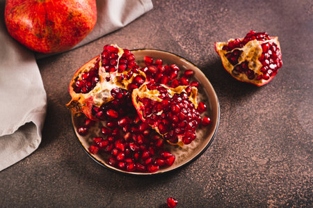 Fresh tasty pomegranate divided into pieces on a plate on the tableの写真素材