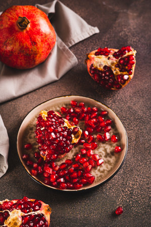 Fresh tasty pomegranate divided into pieces on a plate on the table vertical viewの写真素材