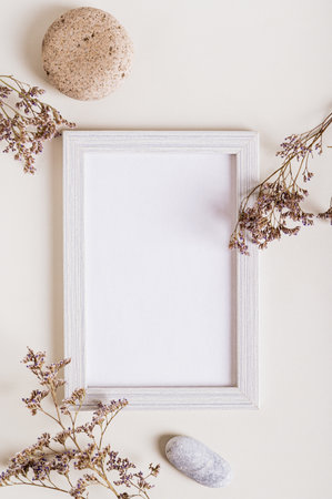 Empty photo frame, dried flowers and stone on a light background top and vertical viewの写真素材