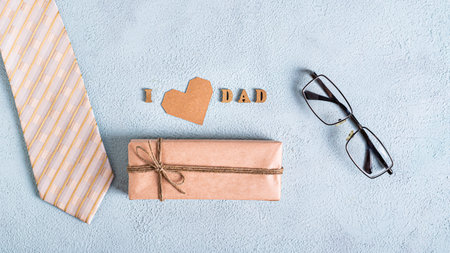 Father's day craft gift, cardboard heart, tie, glasses and inscription on a blue backgroundの写真素材