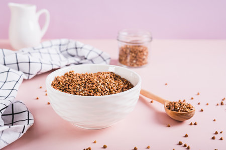 Raw buckwheat in a bowl and wooden spoon on the tableの写真素材