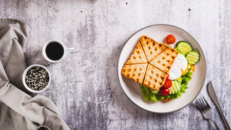 Poached egg with cucumber, tomato and lettuce on waffle toast on a plate top view web bannerの写真素材