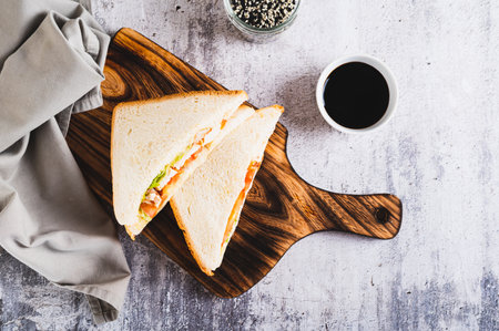 Appetizing sandwich with chicken breast, tomatoes, lettuce and sauce on a board top viewの写真素材
