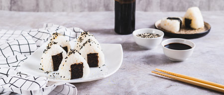 Onigiri traditional Japanese food of rice and tuna on a plate on the table web banner