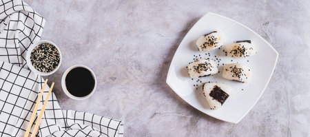 Homemade onigiri rice balls with tuna and nori on a plate on the table top view web bannerの写真素材