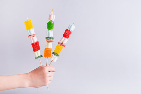 Gummy candy kabobs on skewers holding in a handの写真素材