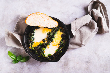 Closeup of green shakshuka with basil and green onions in a frying pan on the table top viewの写真素材