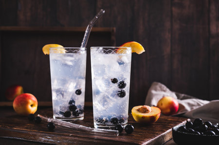 Refreshing lemonade with blackcurrant, nectarine and ice in glasses on the tableの写真素材